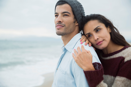 Pensive brunette couple looking at ocean